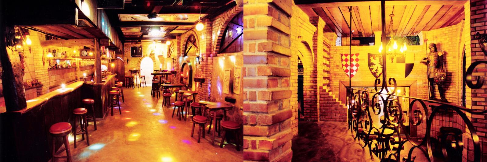 Interior acolhedor da Taverna Pub com tijolos, madeira e iluminação âmbar